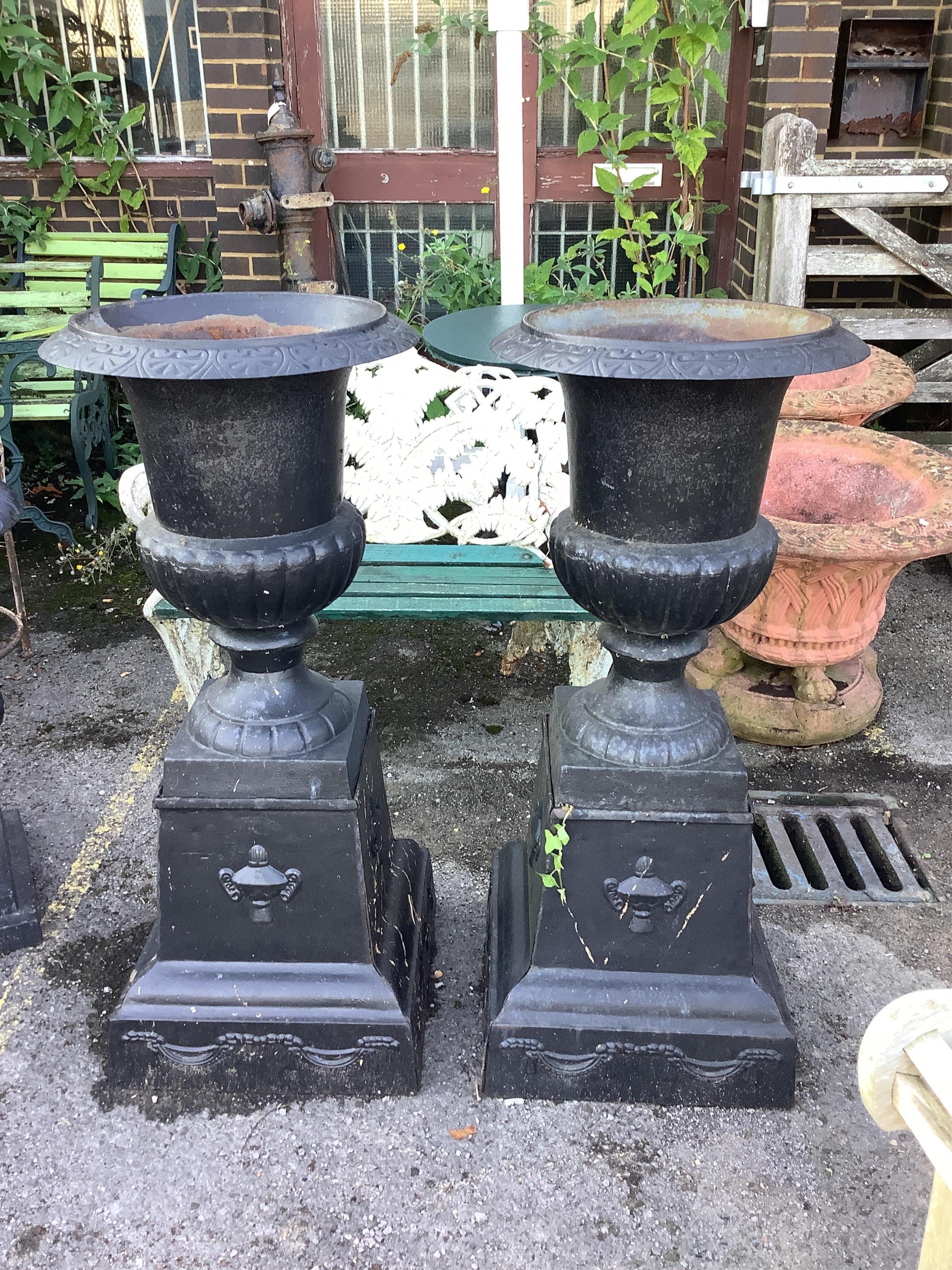 A pair of Victorian style black painted cast iron campana shaped garden urns, on square plinths, diameter 50cm, height 113cm. Condition - fair